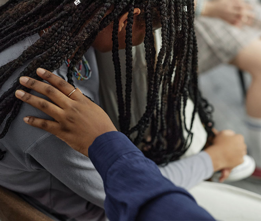 in the news photo with an african american person with a hand on their shoulder for comfort